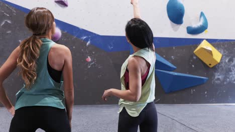 Unrecognizable-women-standing-near-climbing-wall-in-gym