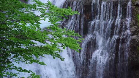 Waterfall-on-cliff-in-mountains-near-trees
