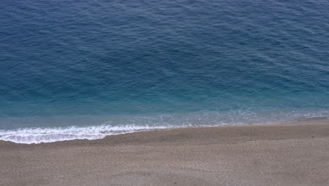Empty-sandy-beach-with-wavy-blue-water