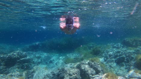 Hombre-Nadando-Bajo-El-Agua-En-Agua-Clara-Usando-Máscara-De-Snorkel-Mostrando-Los-Pulgares-Hacia-Arriba
