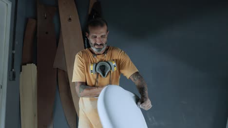 Focused-man-using-sandpaper-on-surfboard