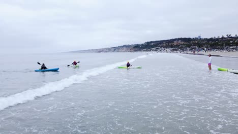 Static-wide-view-of-kayaker-paddling-towards-beach-and-getting-caught-by-waves