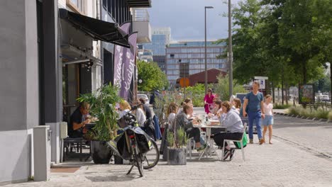 Gente-Feliz-Se-Reúne,-Come-Y-Bebe-En-La-Terraza-De-Un-Bar-En-El-Centro-De-La-Ciudad-Urbana-De-Amberes,-Bélgica---Cámara-Lenta