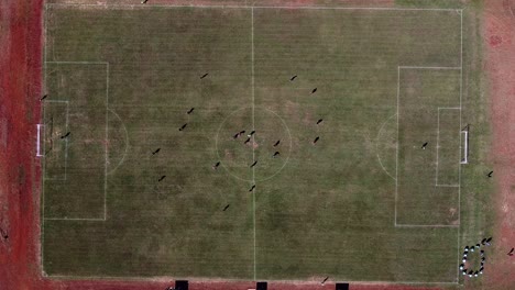 Drone-static-look-down-on-football-pitch,-ball-passed-between-team-players-and-other-players-train-on-the-sidelines