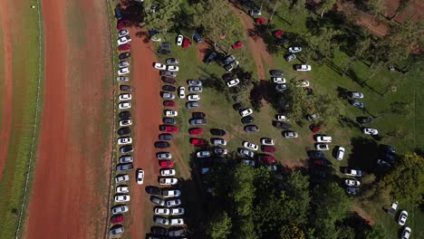 Drone-look-down-on-cars-parked-in-wooded-area-revealing-traffic-on-nearby-road---pan-left-to-right