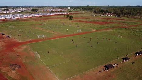 Drone-orbit-around-multiple-multiple-football-matches,-one-match-in-the-foreground-and-two-in-the-background---Posadas-hipodrome