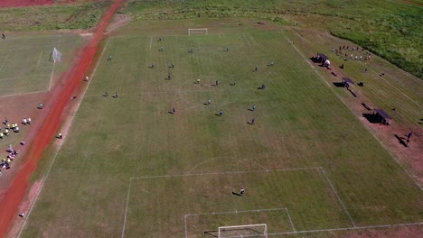 Drohnen-Umlaufbahn-Um-Fußballspieler,-Die-Das-Spielfeld-Betreten,-Und-Den-Blick-Auf-Andere-Fußballfelder-In-Der-Nähe-Freigibt-–-Spieler-Trainieren-An-Der-Seitenlinie