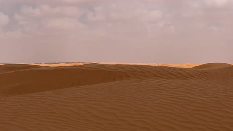Farbkontrast-Der-Sahara-Wüste-Mit-Strahlender-Sonne-Und-Wolken,-Die-Sich-über-Sandige,-Wellige-Oberfläche-Bewegen