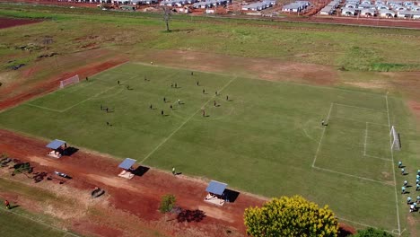 Drone-zipline-onto-football-match,-players-running-across-the-field