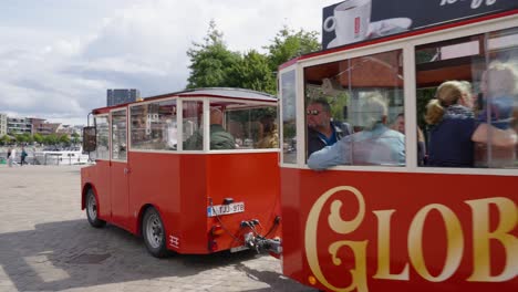 Tourists-ride-on-a-vintage-tourist-shuttle-bus-in-the-city-center-near-the-MAS-Museum-in-Antwerp,-Belgium