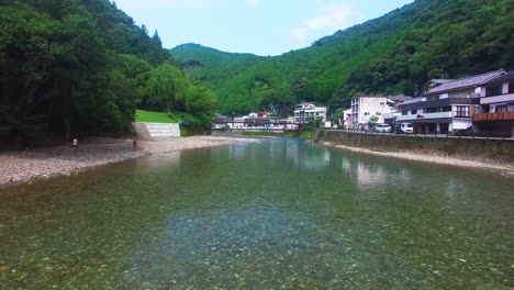 Una-Toma-Aérea-Desde-Un-Dron-Muestra-El-Río-De-La-Aldea-De-Koyasan,-Acercándose-A-Las-Personas-Que-Se-Bañan-Tranquilamente-En-El-Río.