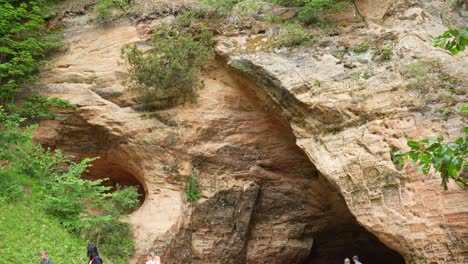 Gente-Frente-A-La-Histórica-Cueva-De-Gutman-En-El-Parque-Nacional-Gauja,-Inclinada-Hacia-Arriba