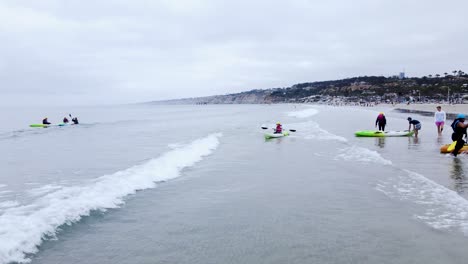 Open-ocean-kayakers-beach-on-shores-of-cloudy-coast,-La-Jolla