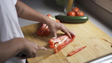 Anonymous-focused-man-cutting-bell-pepper-on-chopping-board