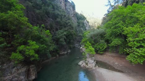 Family-and-Kids-playing-at-sandy-shore-of-Abraham-River-between-green-mountains-in-summer,-Lebanon---Aerial-drone-flight