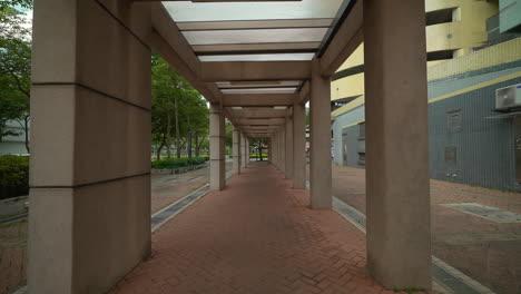 Push-in-through-concrete-pillar-walkway-in-downtown-urban-tropical-location