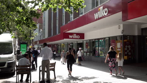 People-walk-past-a-Wilko-superstore-on-a-busy-high-street-in-Stratford-on-a-hot-summer-afternoon