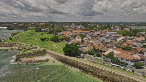 Galle-Sri-Lanka-Aerial-v4-low-flyover-Rampart-street-toward-Cricket-stadium-capturing-sea-fort-on-peninsula,-cityscape-with-buildings-from-Portuguese-colonial-era---Shot-with-Mavic-3-Cine---April-2023