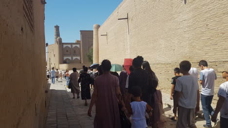 Crowd-of-People-Walking-on-Cobbled-Stone-Street-in-Old-Walled-City-of-Khiva,-Uzbekistan,-UNESCO-World-Heritage-Site