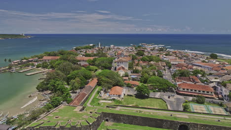 Galle-Sri-Lanka-Aerial-v7-drone-flyover-Cricket-stadium-across-coastal-city-towards-peninsula-beach-capturing-historical-fort,-lighthouse-and-Indian-ocean-views---Shot-with-Mavic-3-Cine---April-2023