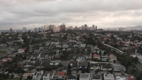 Aerial-forward-flight-over-Suburb-neighborhood-in-Sao-Paulo-and-Skyline-in-Background-during-Cloudy-day