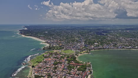 Galle-Sri-Lanka-Aerial-v8-cinematic-high-altitude-drone-flyover-Palm-Island-capturing-sea-fort-on-the-peninsula,-coastal-beach-and-colonial-downtown-cityscape---Shot-with-Mavic-3-Cine---April-2023