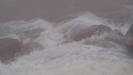 Close-up-of-fast-flowing-glacier-river-in-remote,-stony-and-foggy-environment
