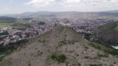 Advance-aerial-shot-revealing-the-city-of-Guanajuato-behind-a-hill