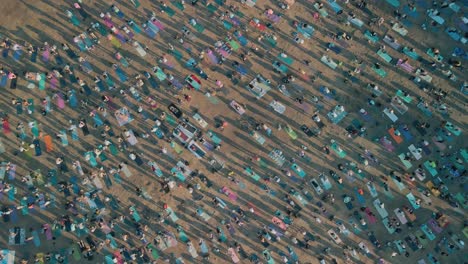 Thousands-gather-in-public-park-raising-arms-doing-yoga,-aerial-bird's-eye-view