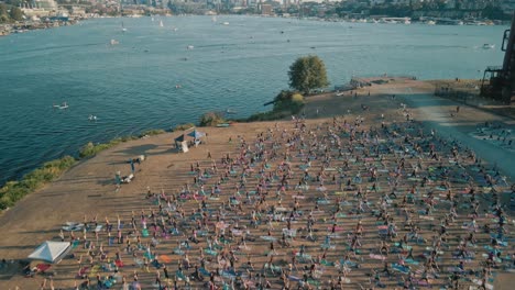 Hundreds-of-people-strike-yoga-warrior-pose-in-public-park,-seattle,-aerial-dolly-tilt-up