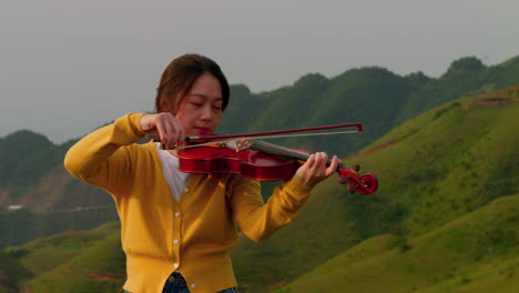 female-musician-in-a-trance-like-state-as-she-plays-the-violin-in-the-mountains