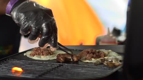 Cut-pork-placed-onto-hot-barbecue-grill-with-small-tongs,-filmed-as-close-up-shot-in-slow-motion-style