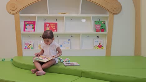 Cute-toddler-reading-books-in-children's-reading-area-of-store