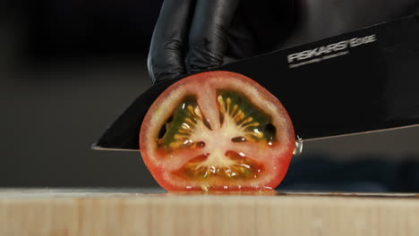 A-top-down-camera-tilt-shows-a-lamp,-a-tomato-being-cut,-and-a-black-background