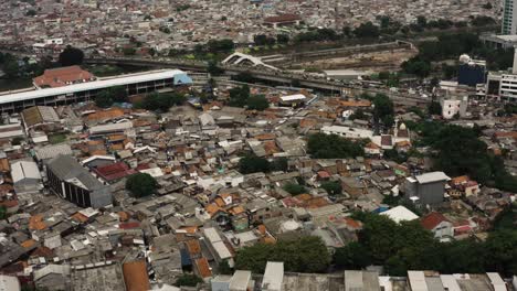 Luftaufnahme-über-Das-Arme-Slumviertel-Der-Stadt-Jakarta-Mit-Der-Skyline-Im-Hintergrund---Grenze-Zwischen-Luxus-Und-Armut