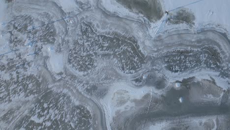 Beautiful-winter-textures-on-display-in-this-top-down-drone-shot-over-a-frozen-lake-and-landscape