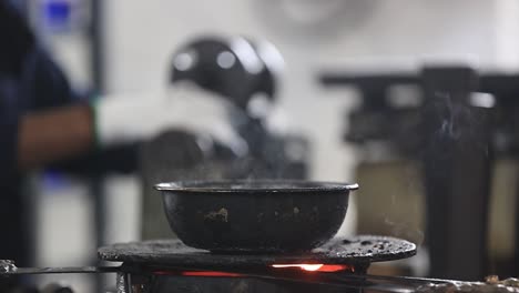 An-employee-wearing-safety-goggles-attaches-a-wax-mold-to-a-component-in-an-investment-casting-foundry