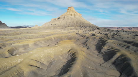 Drone-Shot-of-Barren-Dry-Hills-and-Desert-Landscape-Under-Factory-Butte-Rock-Formation,-Utah-USA