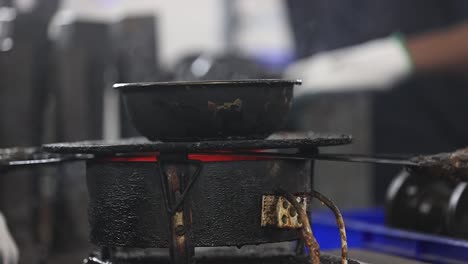 Close-up-scene-showing-wax-being-heated-on-a-court-stove-with-smoke-billowing-from-it