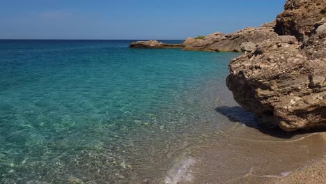 Paradiesischer-Strand,-Umgeben-Von-Klippen-Und-Kristallklarem-Meerwasser-Mit-Blau-türkisfarbenen-Sommerfarben-Am-Mittelmeer