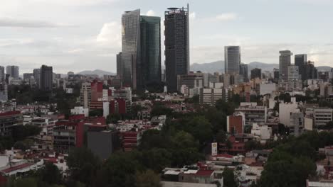 Living-district-and-reveal-of-Mexico-city-skyscrapers,-aerial-view