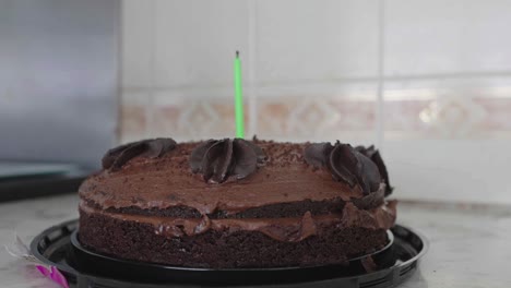 Chocolate-birthday-cake-with-one-candle-being-lit