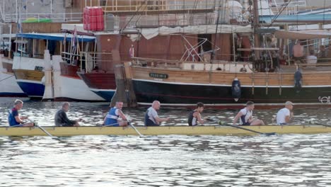 Neun-Ruderer-Passieren-Angedockte-Schiffe-Im-Hafen-Der-Altstadt-Von-Zadar,-Kroatien