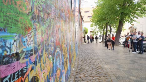 walk-along-John-Lennon-Wall-covered-Graffiti-in-In-Prague,-Czech-Republic