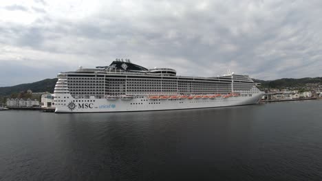 MSC-Prezioza-cruise-ship-is-moored-alongside-in-port-of-Molde-Norway---Wide-angle-view-from-filmed-seaside-on-passing-vessel