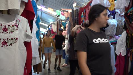 Toma-En-Cámara-Lenta-De-Turistas-Caminando-Por-Una-Fila-Dentro-De-Los-Mercados-Mexicanos.