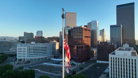 American-and-Colorado-flags-waving-in-front-of-Denver,-CO-skyline