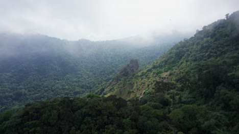 Misty-mountain-rainforest-aerial-flight-through-cloud-to-rock-spire