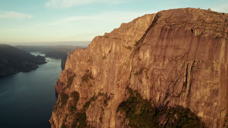Atemberaubende-Luftaufnahme-Einer-Beeindruckenden-Klippe-In-Norwegen,-Sonnenaufgangsatmosphäre-Im-Lysefjord,-Preikestolen,-Kanzelfelsen,-Drohne-Beim-Aufsteigen