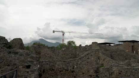 Construction-Crane-Seen-In-Background-Of-Ruins-Of-Pompeii-With-Mount-Vesuvius-In-Background-With-Clouds-Overhead